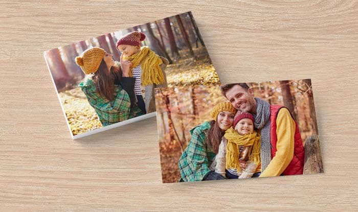 Duas fotografias de família impressas em 15×20 sobre uma mesa de madeira clara, uma deitada e outra ao alto