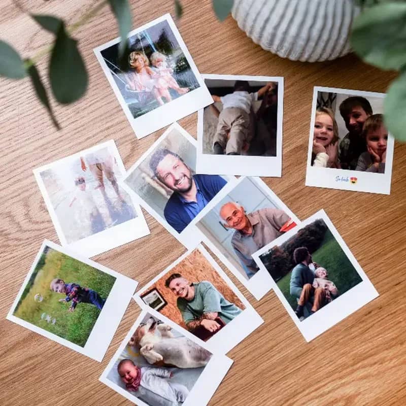 Várias impressões polaroid espalhadas numa mesa de madeira, cada uma com uma frase escrita à mão na margem branca