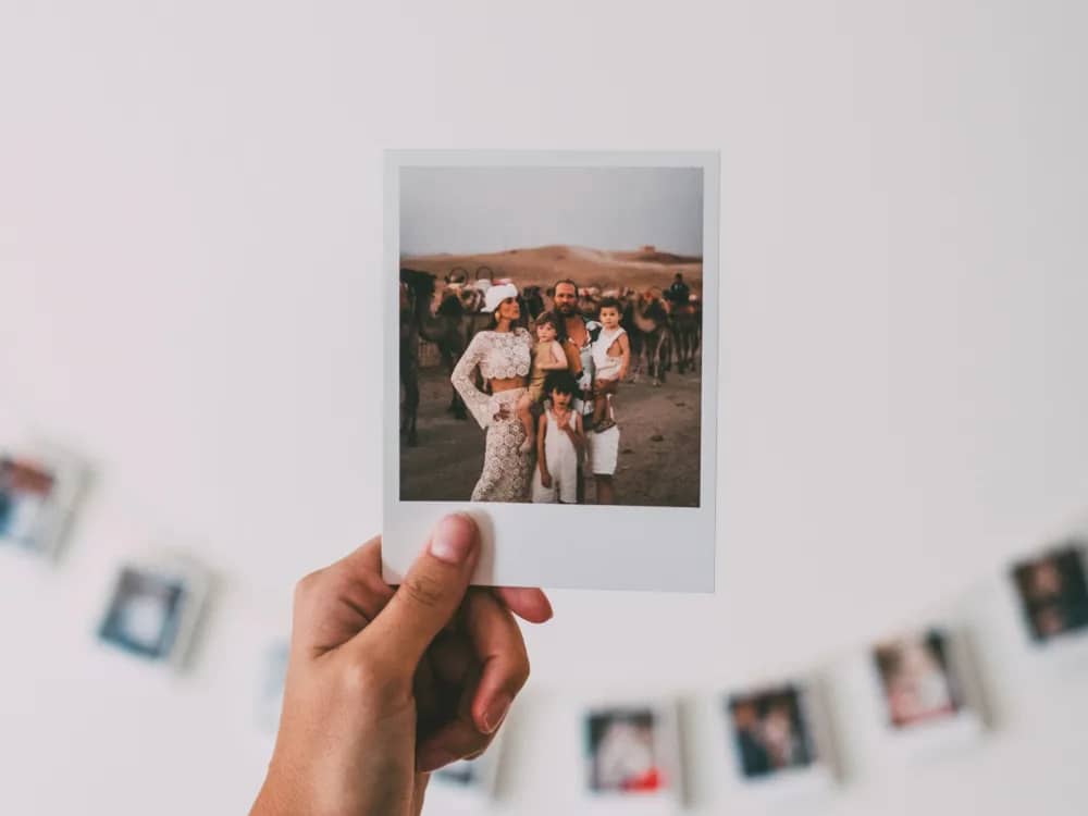 Várias impressões polaroid presas com fita numa parede clara, em duas filas
