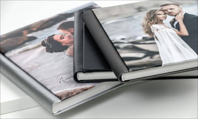 Dois álbuns impressos de capa dura, fechados e empilhados, com a fotografia do casal na capa e a lombada à vista