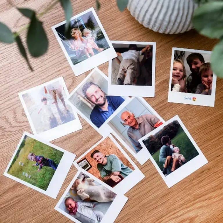 Várias polaroids com margem branca espalhadas numa mesa de madeira