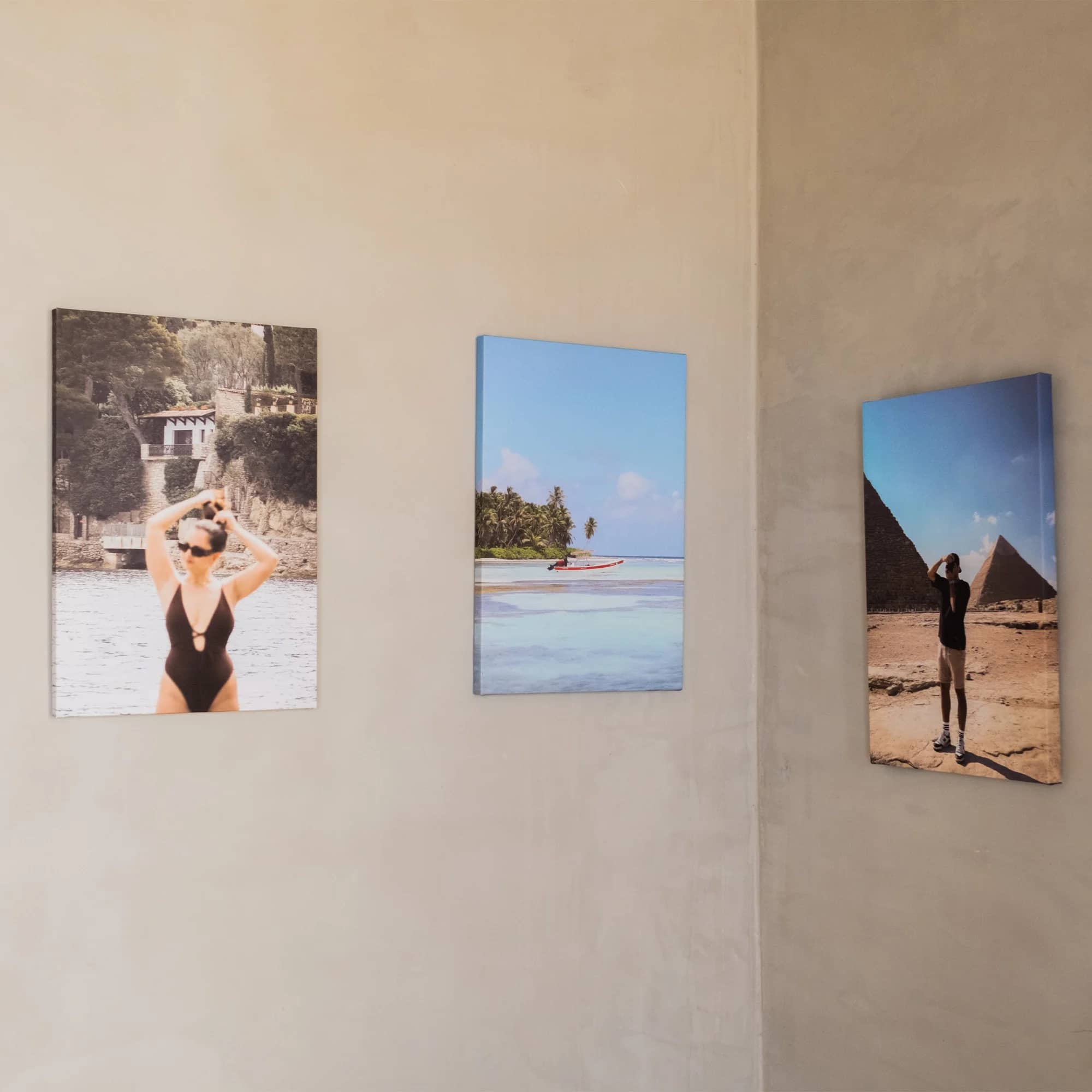 Canto de uma sala de paredes claras com três fotografias de viagem penduradas