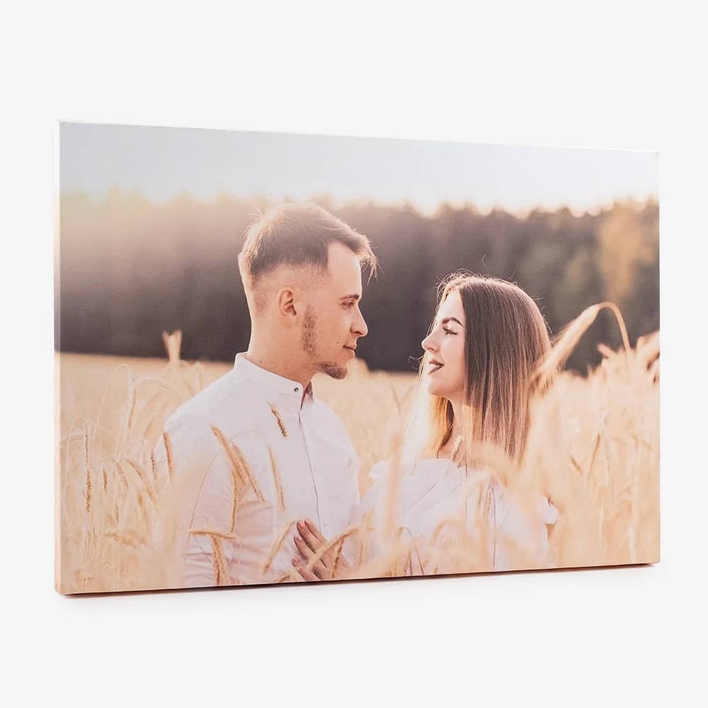 Tela com a fotografia de um casal num campo de trigo ao fim da tarde, vista de lado